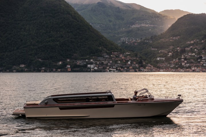 Boat on a lake with mountains and houses in the background at sunset.