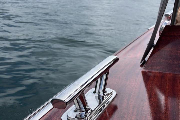 Polished boat deck with a cleat on a lake, hills in background.