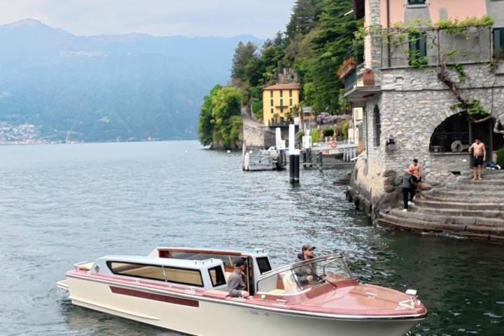 Boat on lake near shore with buildings and trees.