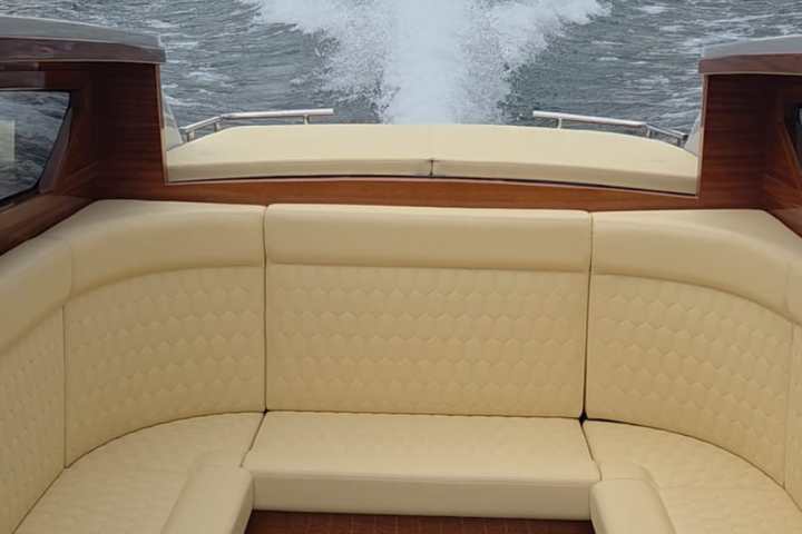 View of lake and mountains from the back of a boat with yellow seating.