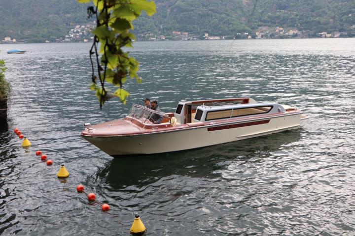 Wooden boat on a lake with mountainous background and hanging vine leaves.