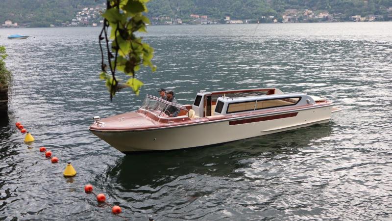 Wooden boat on a lake with mountainous background and hanging vine leaves.